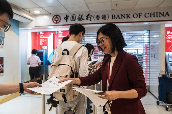 A Bank of China employee in Hong Kong hands out information on opening a new account with the branch on May 4. Photo: VCG