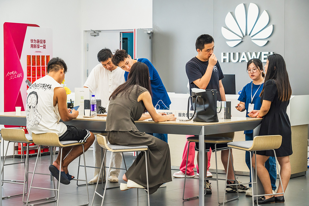 Shoppers examine mobile phones at a Huawei store in Qingdao, Shandong province, on Aug. 10. Photo: VCG